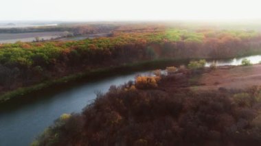 Sonbahar boyunca nehir manzarası ve Rusya 'nın güzel kırsal bölgeleri. Sonbahar renk ormanı manzarası, güneşli bir sonbahar gününde renkli ağaçların üzerindeki hava manzarası. Sonbahar insansız hava aracı üst görünümü.