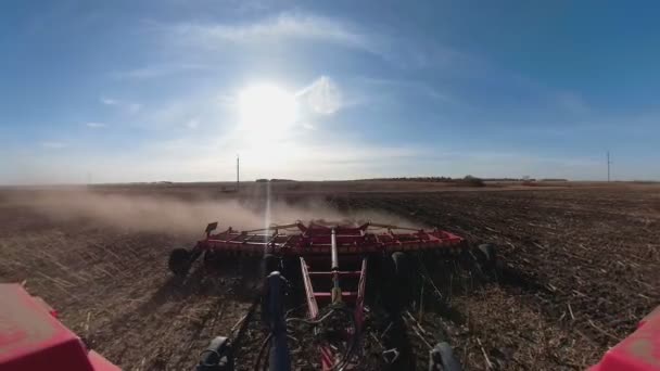 Vue arrière du tracteur avec système de herse labourant sur un champ agricole cultivé, pilier de pistes de poussière derrière, préparation du sol pour la plantation de nouvelles cultures — Video