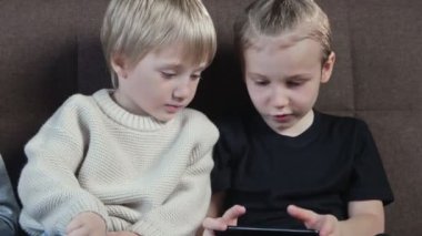 Evde akıllı telefondan oyun oynayan sevimli anaokulu çocukları.