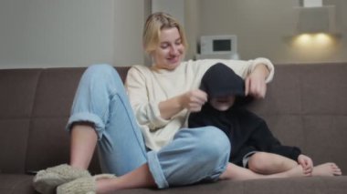 Genç anne oğluyla kanepede oturur, televizyon izler ve birlikte konuşur.