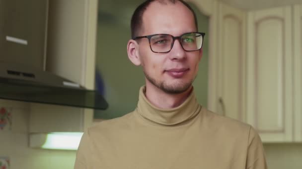 Mężczyzna w okularach je czekoladowe ciasteczka w kuchni — Wideo stockowe