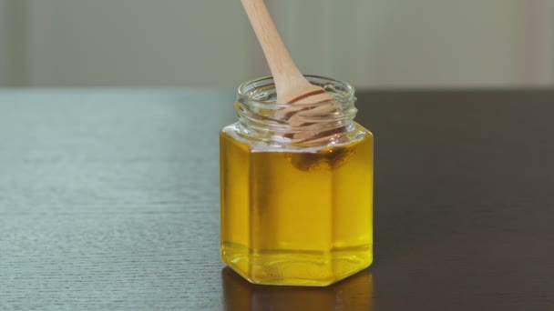 Flytande ekologisk rå honung i glasburk med trä honung dipper. — Stockvideo
