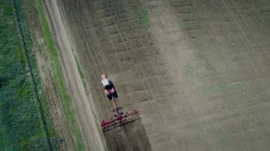 Kırmızı traktörlü çiftçi manzarası küçük arazisinde toprağı sürüyor. Çiftçilik için çalış.