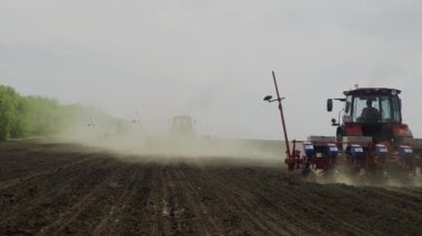 Traktörlerdeki çiftçiler bahar günü tarım tarlasına tohum ekiyor.