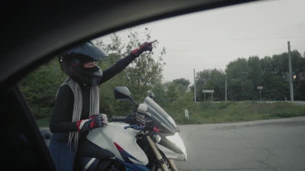 Jeune femme dans un casque noir assis sur la moto et parle avec le conducteur de voiture — Video