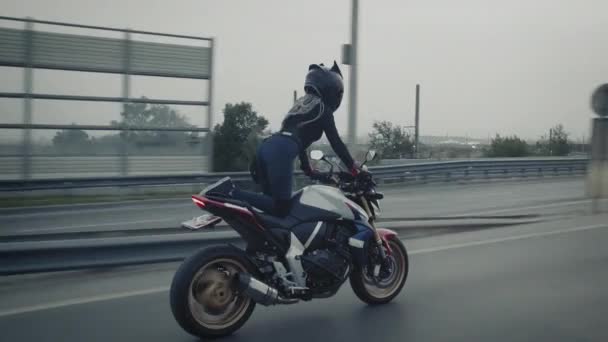 Jovem louca mulher em um capacete preto faz truques em moto — Vídeo de Stock