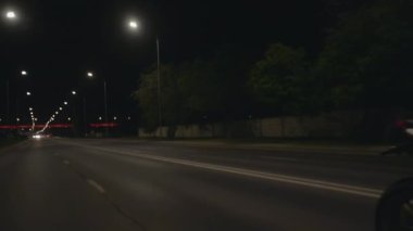 Siyah kasklı genç bir kadın motosiklet sürüyor ve kameraya kalbi gösteriyor.