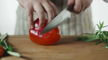 Erkek elleri bıçakla tahta bir tahtada biber kesiyor.