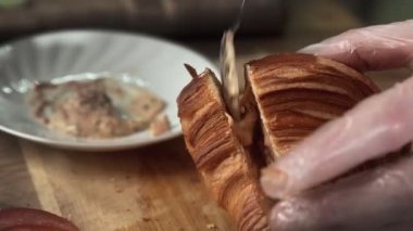 Şefe yakın mesafeden enfes kruvasan sandviçi yapar. Şef kruvasana sos koydu.
