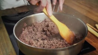 Şef kızartma tavasında et doğruyor.