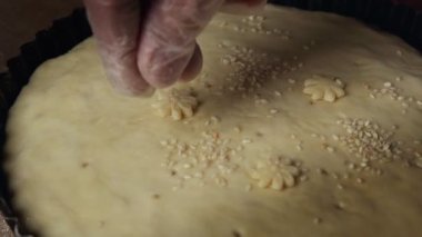 Profesyonel şef etten turta yapar. Şef etli turtanın üstüne susam koyar.