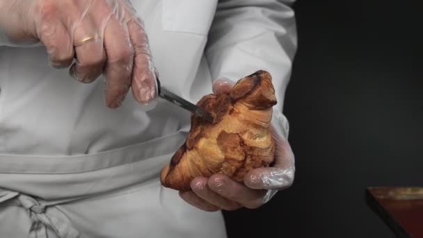 Detailní záběr natáčení samec pečivo kuchař dělá díru s nožem v croissant — Stock video