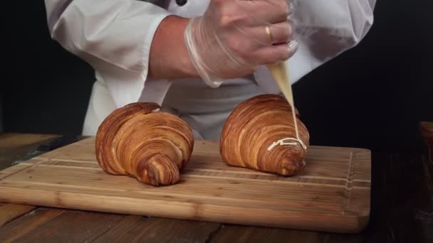 Obchodní pekárna. Kuchař zdobí croissanty pomocí tašky na vaření. — Stock video
