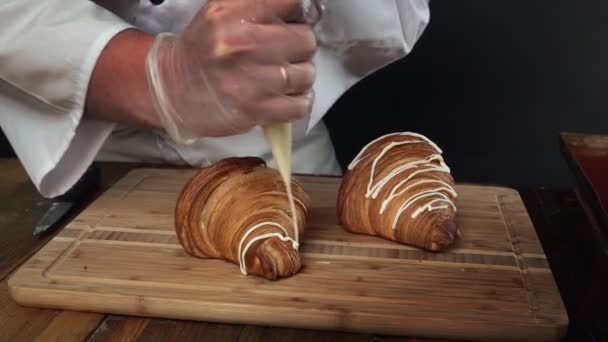 Séf díszíti frissen sült croissant segítségével olvadt csokoládé a pékségben konyha — Stock videók