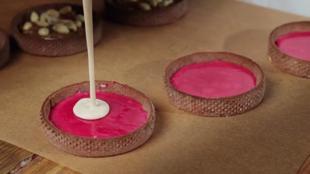 Chef añadiendo crema blanca a las tartas pequeñas con chokolate — Vídeo de stock