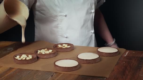 Bucătar adăugând cremă albă la tartele mici alune — Videoclip de stoc