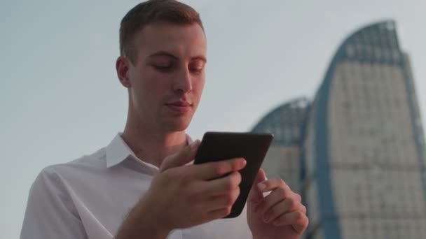 Un gars dans la rue le soir lit un e-book — Video