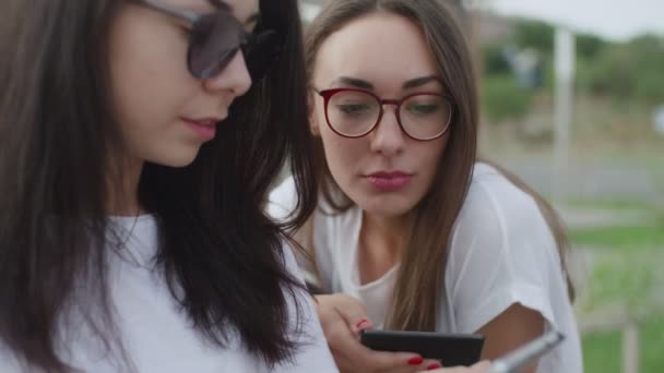 Duas meninas ao ar livre ler um e-book — Vídeo de Stock