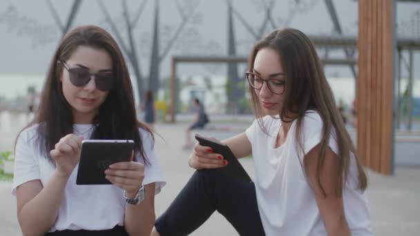 Due ragazze all'aria aperta leggono un e-book — Video Stock