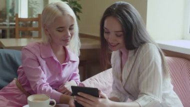 İki kız bir kafede oturup e-kitap okuyor.