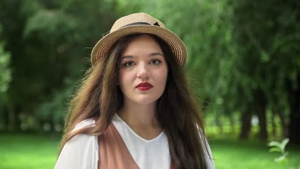 모자를 쓴 아름다운 소녀가 웃으며 여름에 자연 속의 카메라를 바라봅니다 — 비디오