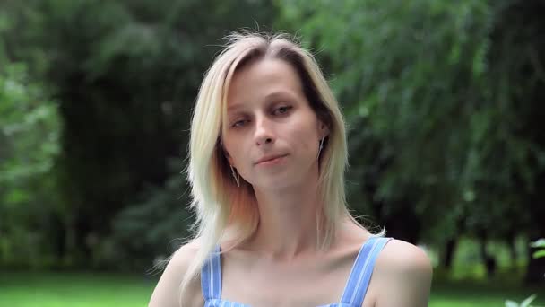 O femeie frumoasă în natură zâmbește și se uită la cameră — Videoclip de stoc