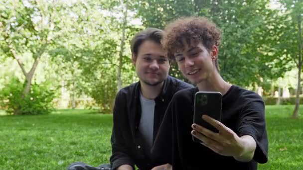 Двоє молодих хлопців фотографувалися по телефону в природі влітку — стокове відео