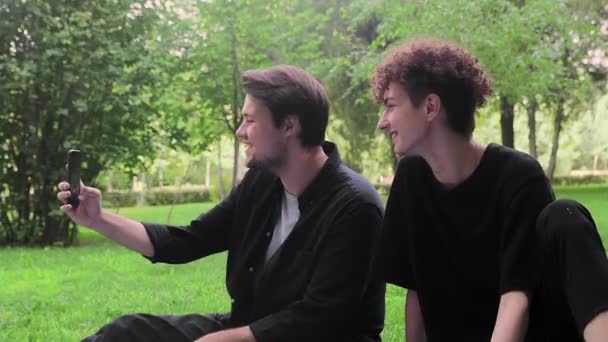 Two young guys are photographed on the phone in nature in the summer — Stock Video