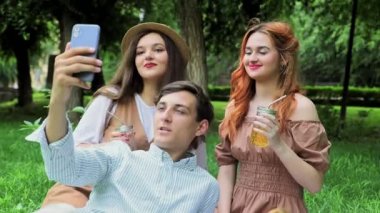 Bir erkek ve iki kız yazın doğada video bağlantısı üzerinden telefonda konuşuyorlar.