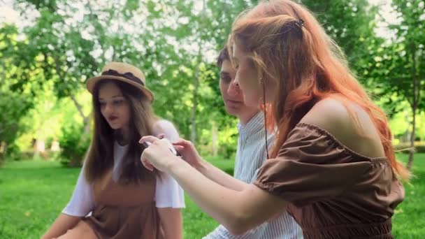 A menina mostra seus amigos fotos no telefone na natureza no verão — Vídeo de Stock