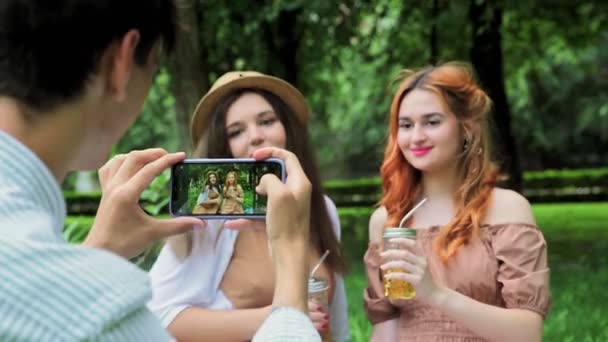 Um cara tira fotos de meninas no telefone no verão na natureza, close-up — Vídeo de Stock
