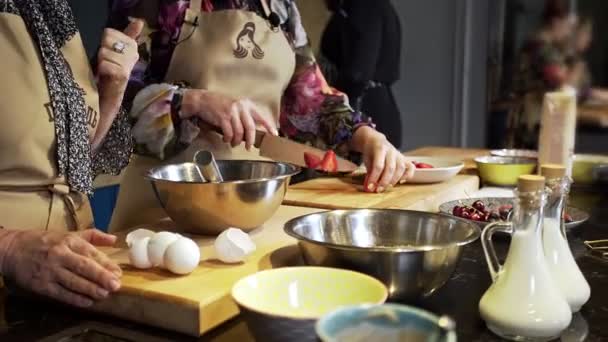 Las mujeres cortan fresas en una tabla de madera en la cocina — Vídeos de Stock