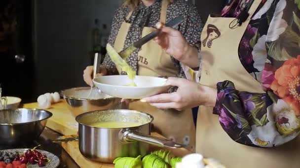 Μια νεαρή μαγείρισσα χύνει ζεστή σούπα από μια κατσαρόλα σε ένα μπολ για μεσημεριανό.. — Αρχείο Βίντεο
