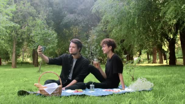 Kaksi nuorta miestä kuvataan puhelimessa luonnossa kesällä. — kuvapankkivideo