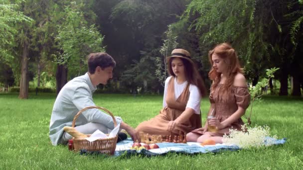 Un tip și două fete au avut un picnic și au început să joace șah în natură în timpul verii — Videoclip de stoc