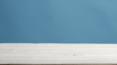 Mantarlar mavi arka planda beyaz ahşap bir masada yuvarlanır.