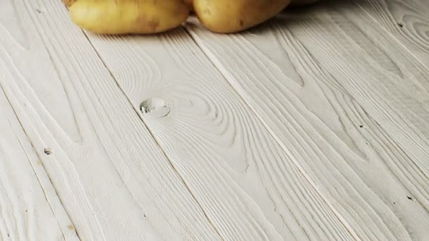 Una papa cruda con un rollo de cáscara sobre una mesa de madera — Vídeos de Stock