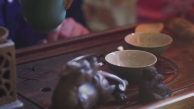 Bir adam çay bardaklarına çay koyar çay odasındaki ahşap tepside