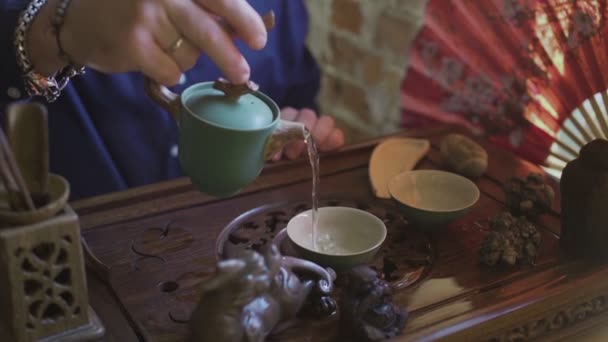 Un hombre vierte té en tazas de té en una bandeja de madera en una sala de té — Vídeo de stock