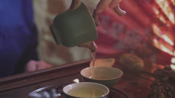 Un uomo versa il tè in tazze da tè su un vassoio di legno in una sala da tè — Video Stock