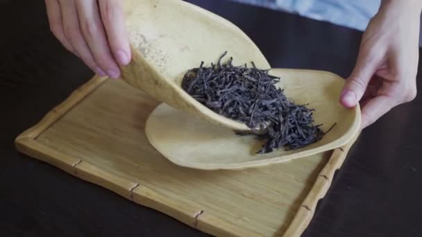 Kvinnors händer överföra teblad från en träskål till en träplatta i te rummet på bordet — Stockvideo