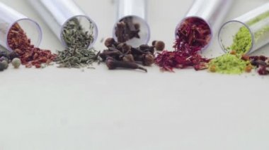 Masanın üzerinde yedi test tüpü var ve her birinde farklı baharatlar ve baharatlar var.
