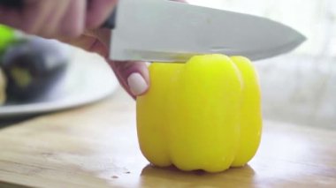 Mutfak bıçağıyla tatlı biberi doğrarken yakın plan.