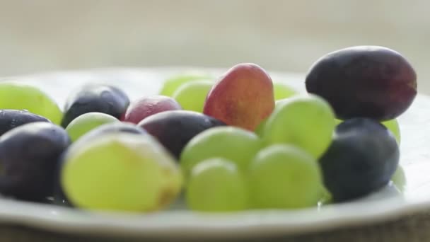 Primer plano de uvas rojas y verdes en un plato — Vídeo de stock