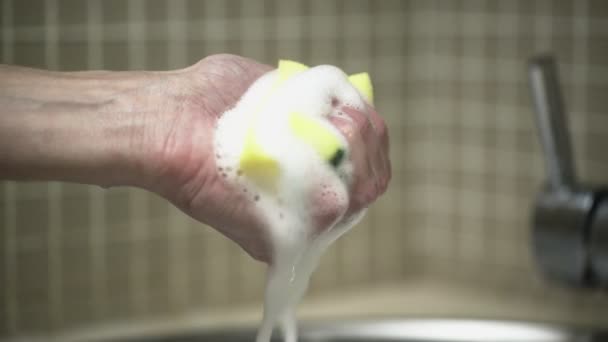 Uma mão de homem na cozinha aperta uma esponja em espuma — Vídeo de Stock