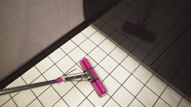 Een vrouw wast de keukenvloer met een roze dweil — Stockvideo