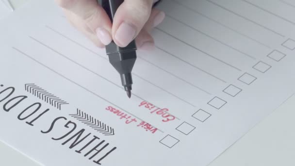 En kvinnlig hand skriver i att-göra-listan vad som behöver göras, närbild — Stockvideo