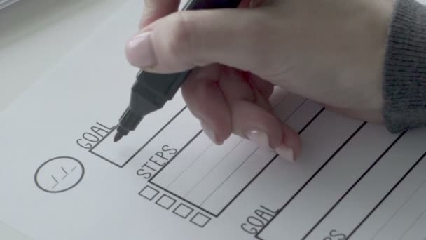 Žena stanovuje cíle tím, že zapíše cíle do svého notebooku s červeným perem close-up — Stock video
