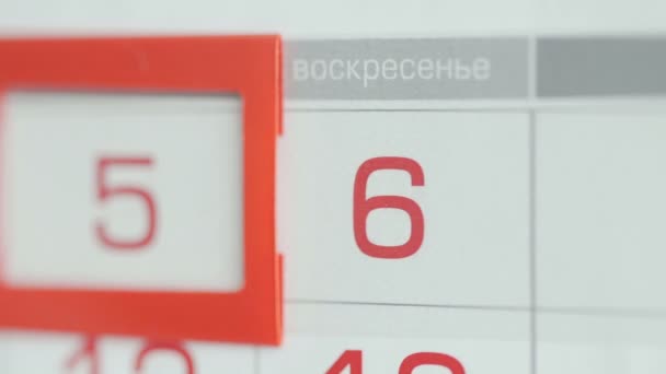 Närbild av en kvinnas finger flyttar datum pekaren på kalendern — Stockvideo