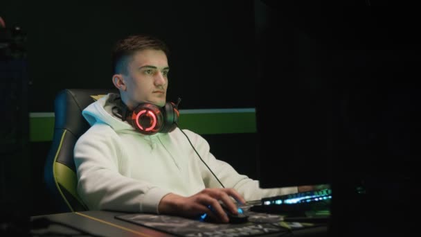 Un joven jugador juega en un ordenador con auriculares — Vídeos de Stock